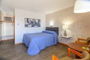 1 bed in 1 bedroom suite with sitting chairs and table at Welsh's Motel in Wall, SD