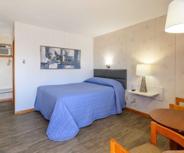 1 bed in 1 bedroom suite with sitting chairs and table at Welsh’s Motel in Wall, SD 1 bed in 1 bedroom suite with sitting chairs and table at Welsh's Motel in Wall, SD