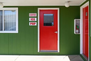 Red office door with green siding and signs that say coffee, ice, pop at Welsh's Motel in Wall, SD